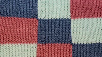 Machine knitted color block pattern using intarsia technique, showing three colors joined without carrying yarn across back