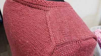 Close-up of a machine-knitted European shoulder showing the distinctive angled seam placement