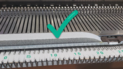 Close-up of a new knitting machine spongebar showing intact, firm foam material that properly maintains needle positions during knitting