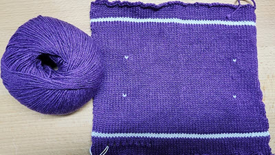 A blocked machine-knitted gauge swatch with visible markers and measuring guides showing how to count both stitches and rows per inch