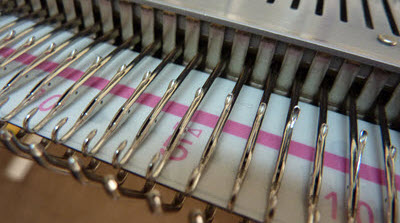 Close-up view of a knitting machine's needle bed, showing the basic mechanical components of a knitting machine.