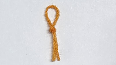 Close-up of a small, handmade yarn marker created from a contrasting color of yarn, showing its simple but effective construction