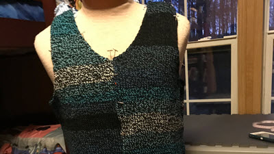 Display of machine knitted sweater in self-striping yarn, revealing how garment width affects stripe patterns