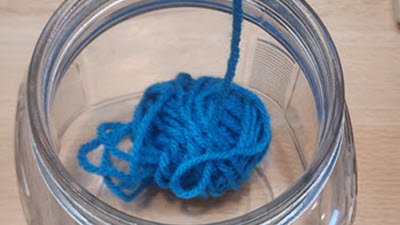 Nearly empty ball of yarn in a glass jar, illustrating the anxiety of yarn chicken