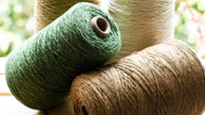 Three cones of machine knitting yarn representing yarn available from specialty suppliers.