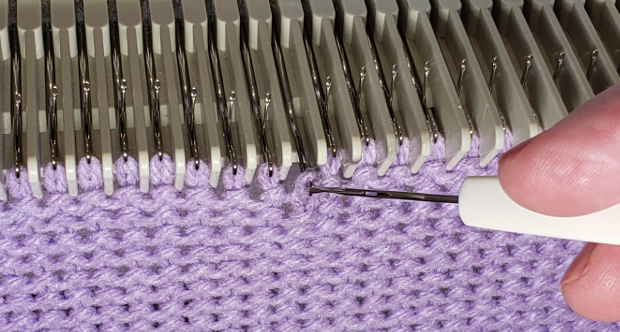 Lift up on the tool, sliding the new stitch over the machine needle