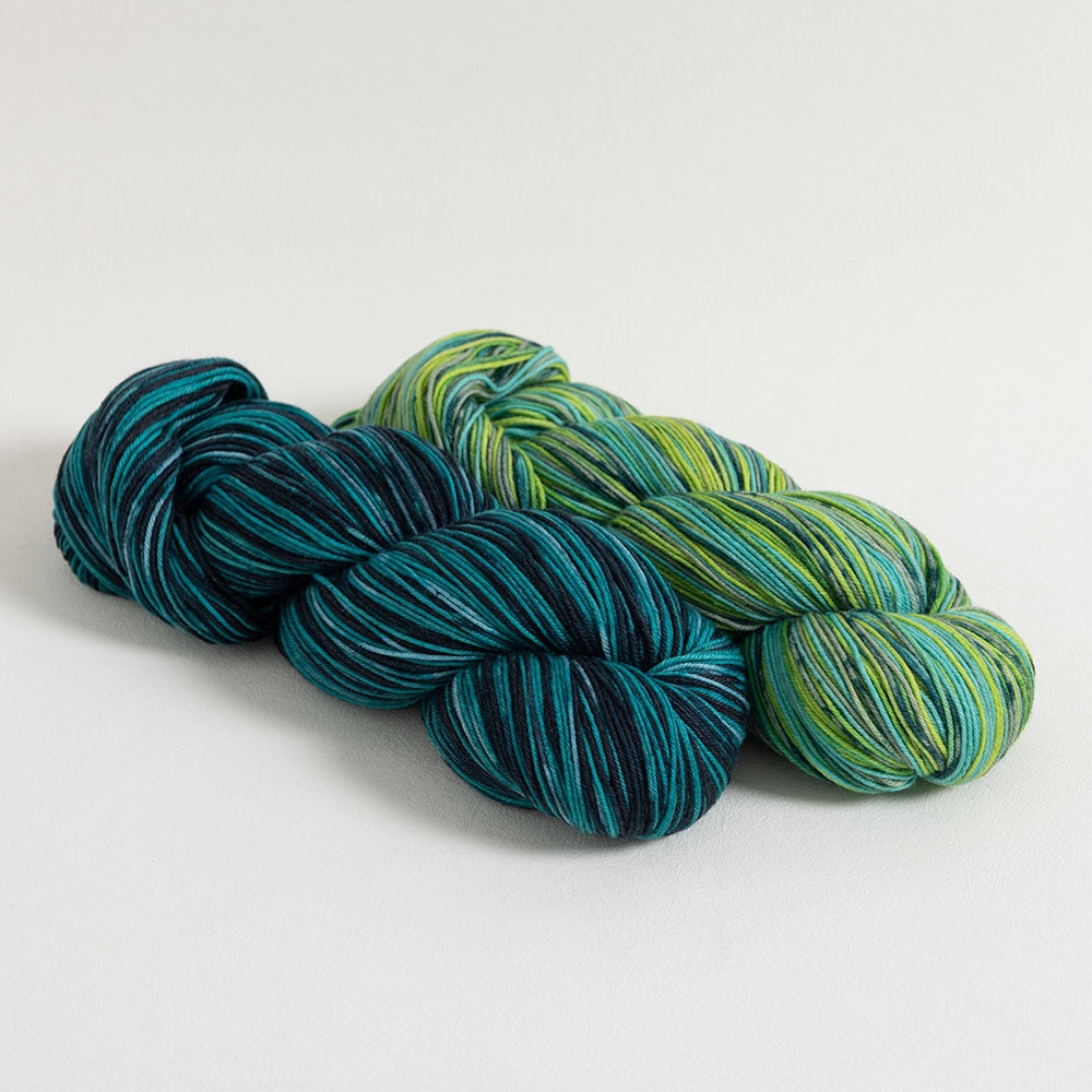 Two skeins of Knit Picks Static self-striping sock yarn in teal and green colorways.