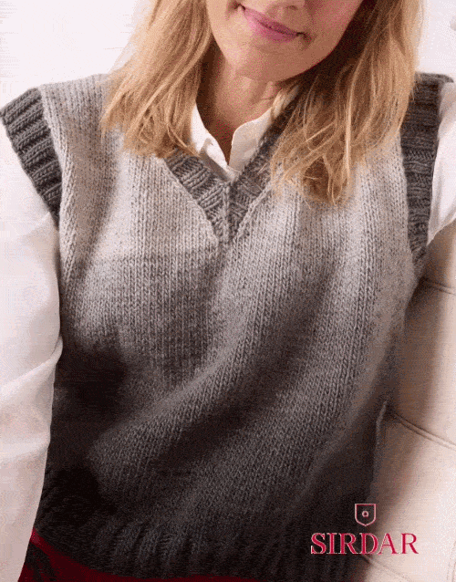 A person wearing a gray ombre V-neck sleeveless pullover with ribbed trim at the neckline, armholes, and hem, layered over a white shirt.
